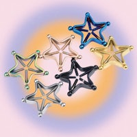 a group of star shaped earrings on a pink background