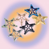 a group of star shaped earrings on a pink background